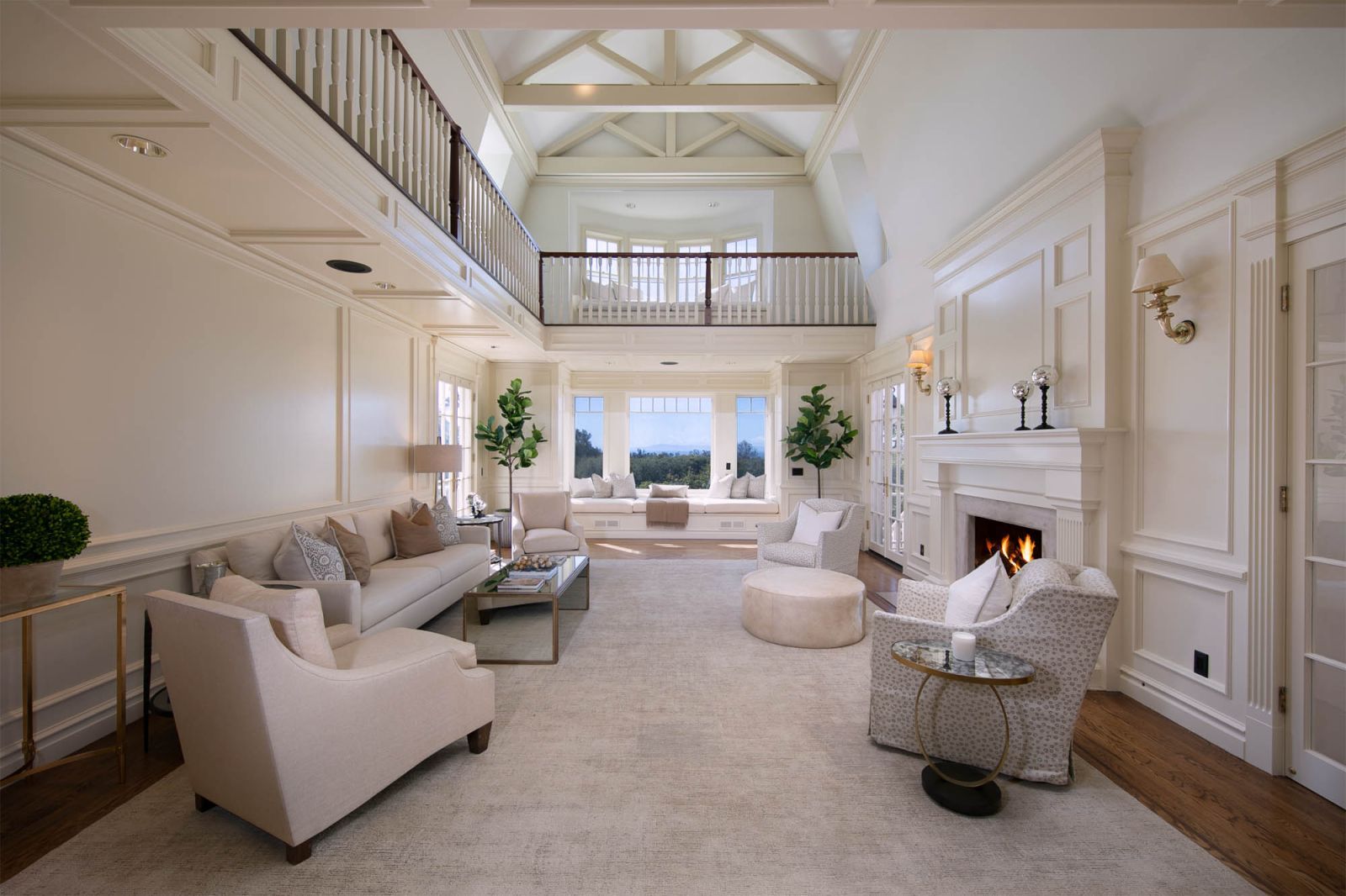 The dramatic all white living room of a luxury home with a soaring open truss vaulted ceiling